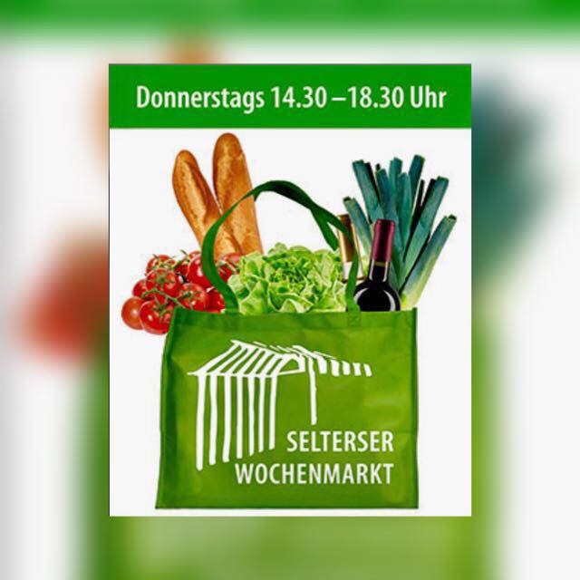 Grüne Einkaufstasche mit Gemüse, Brot, einer Weinflasche und Produkten der Ölmühle Bertgen. Der Text darüber lautet: "Donnerstags 14.30-18.30 Uhr". Auf der Tüte steht "Wochenmarkt Selters".